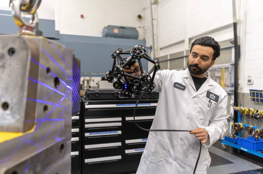 Técnico a digitalizar um molde metálico com scanner laser 3D portátil num laboratório de metrologia